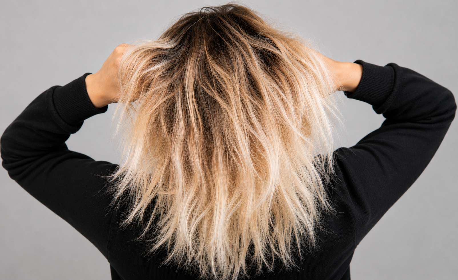 Bleached blonde hair with dark roots and visible dryness, showing damaged texture and uneven strands for hair repair and bond treatment concepts.