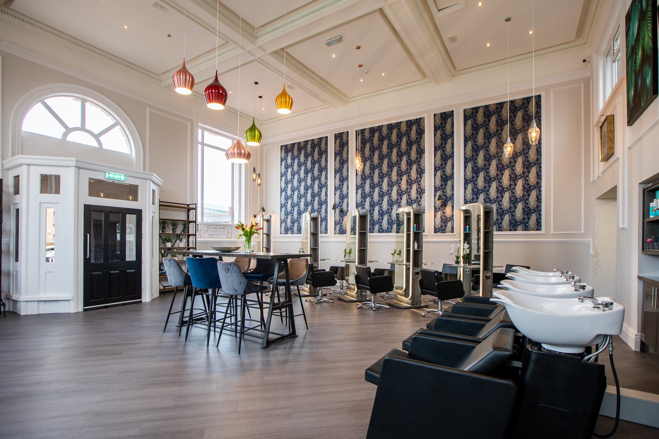 Hair, Beauty, Aesthetics Hull. The main hall of the salon which includes four wash basins, waiting area in the centre with 10 seats, five double sided hairdressing units showing off the high ceilings and pendant lighting