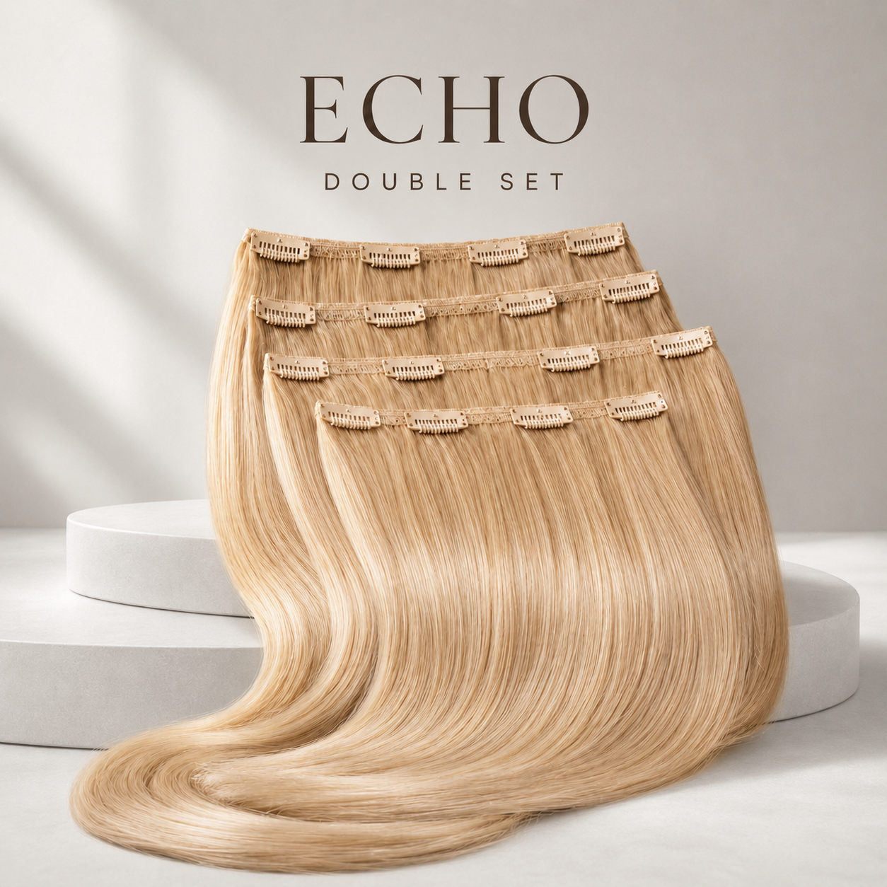 Four long, straight clip-in hair extensions in a light blonde shade are displayed in a layered fan arrangement on white display pedestals, with the text 'ECHO DOUBLE SET' above them.