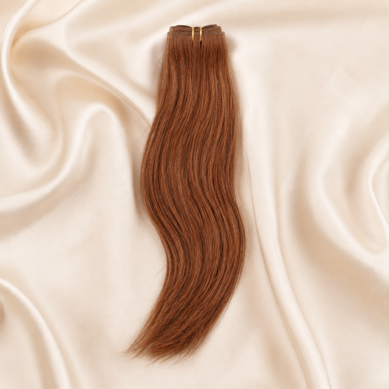 Brown European weft hair extension on a beige satin background